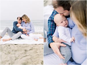 A couple sits on the beach, lovingly holding their baby—captured by a Carlsbad Newborn Photographer with the ocean behind.