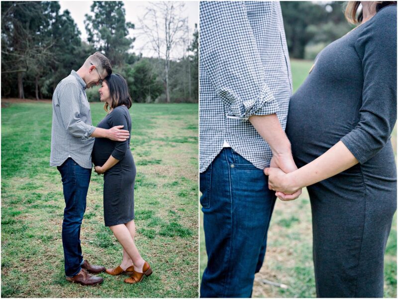 A couple stands close outdoors, touching foreheads and holding hands during their Solana Beach pregnancy photos.