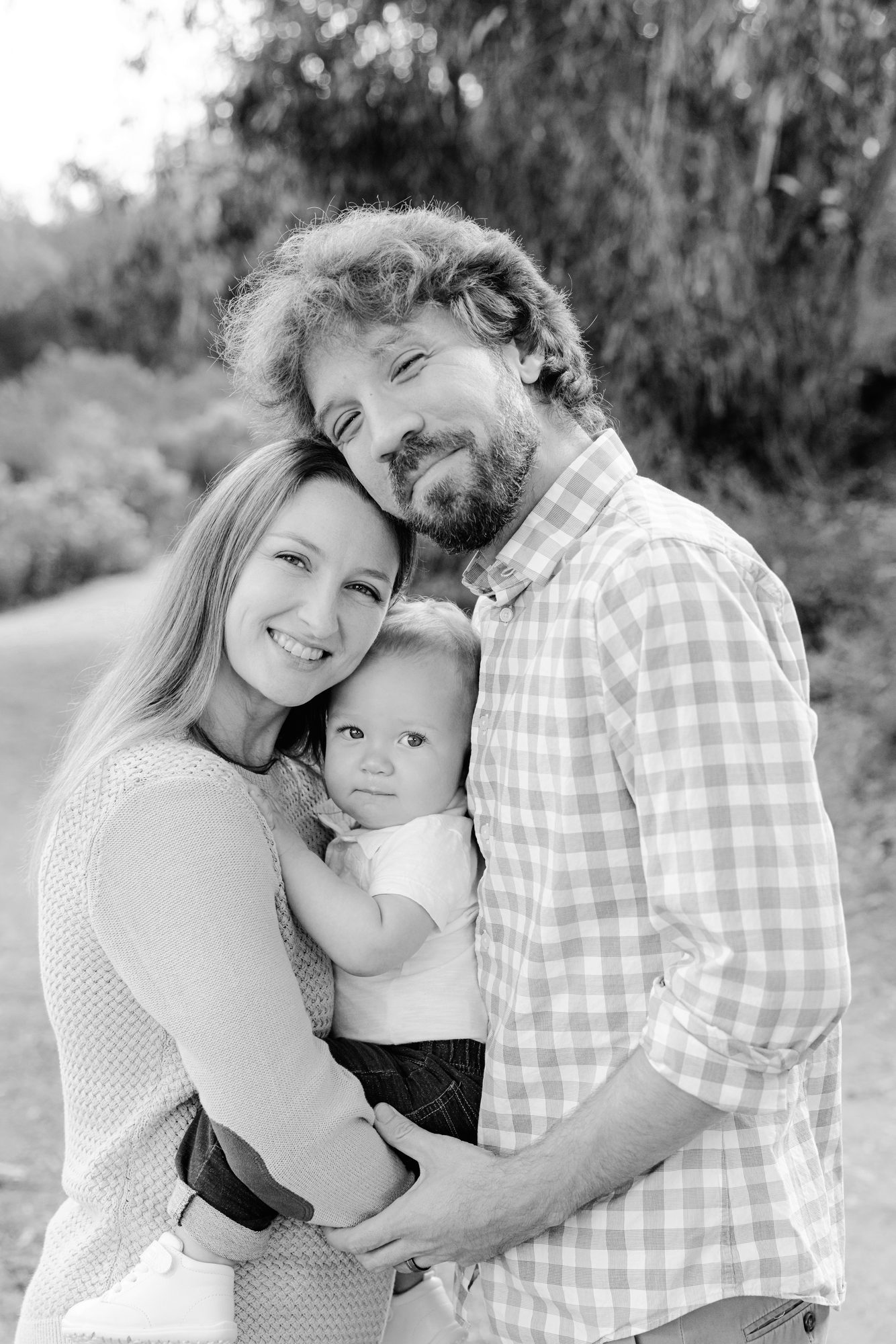 Parents holding their baby close, black and white family portrait