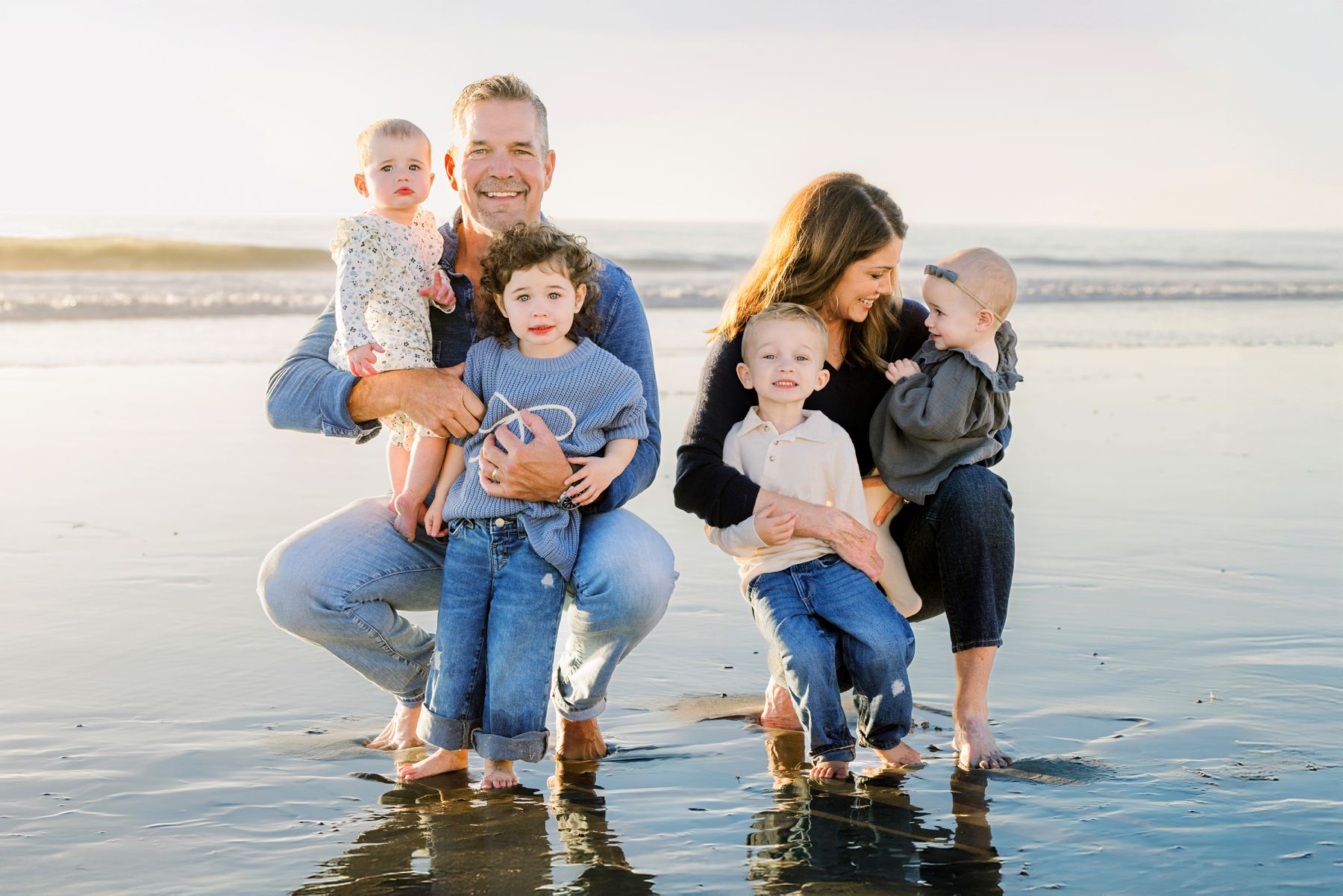 Family of two adults and four children smiling on a sunset beach—captured by a San Diego Family Photographer.