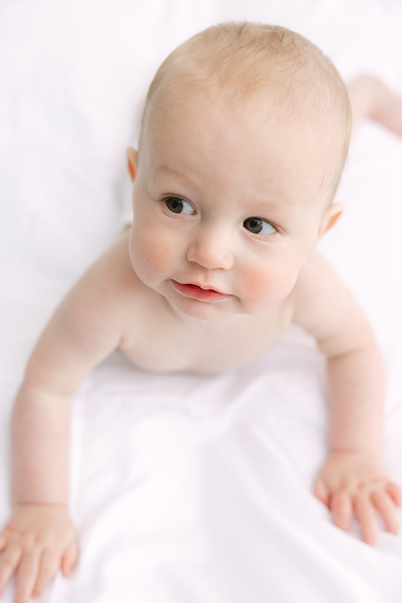 Baby boy crawling on a white bed, studio baby portrait