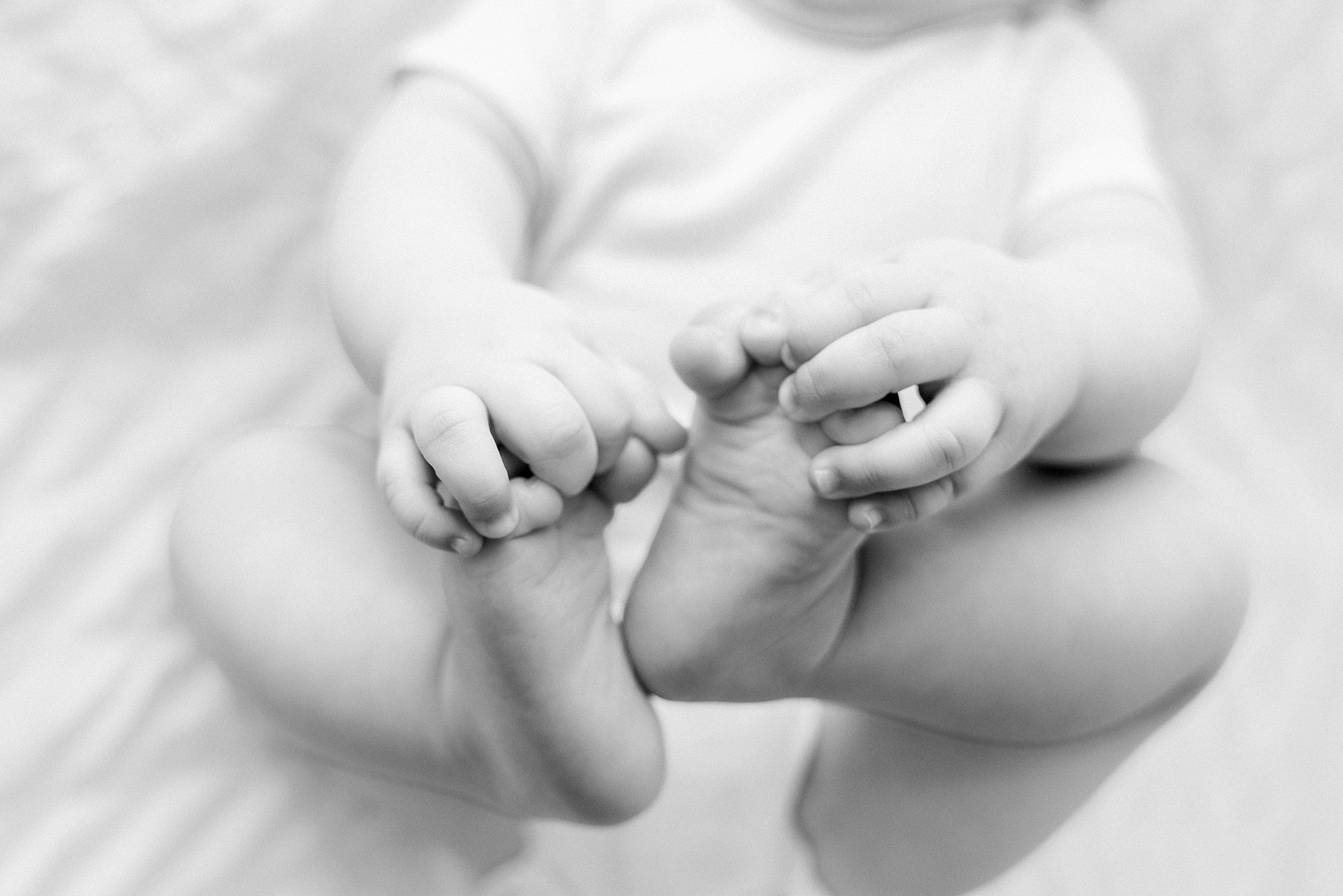 A babys hands holding their own feet.