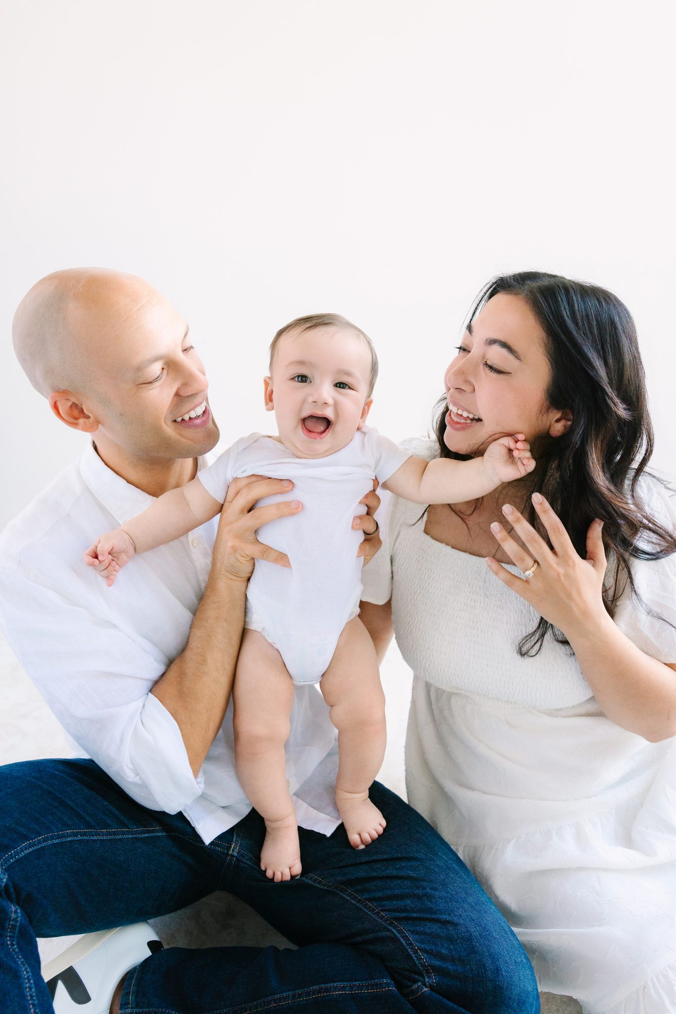 Parents holding up their smiling baby, studio family portrait