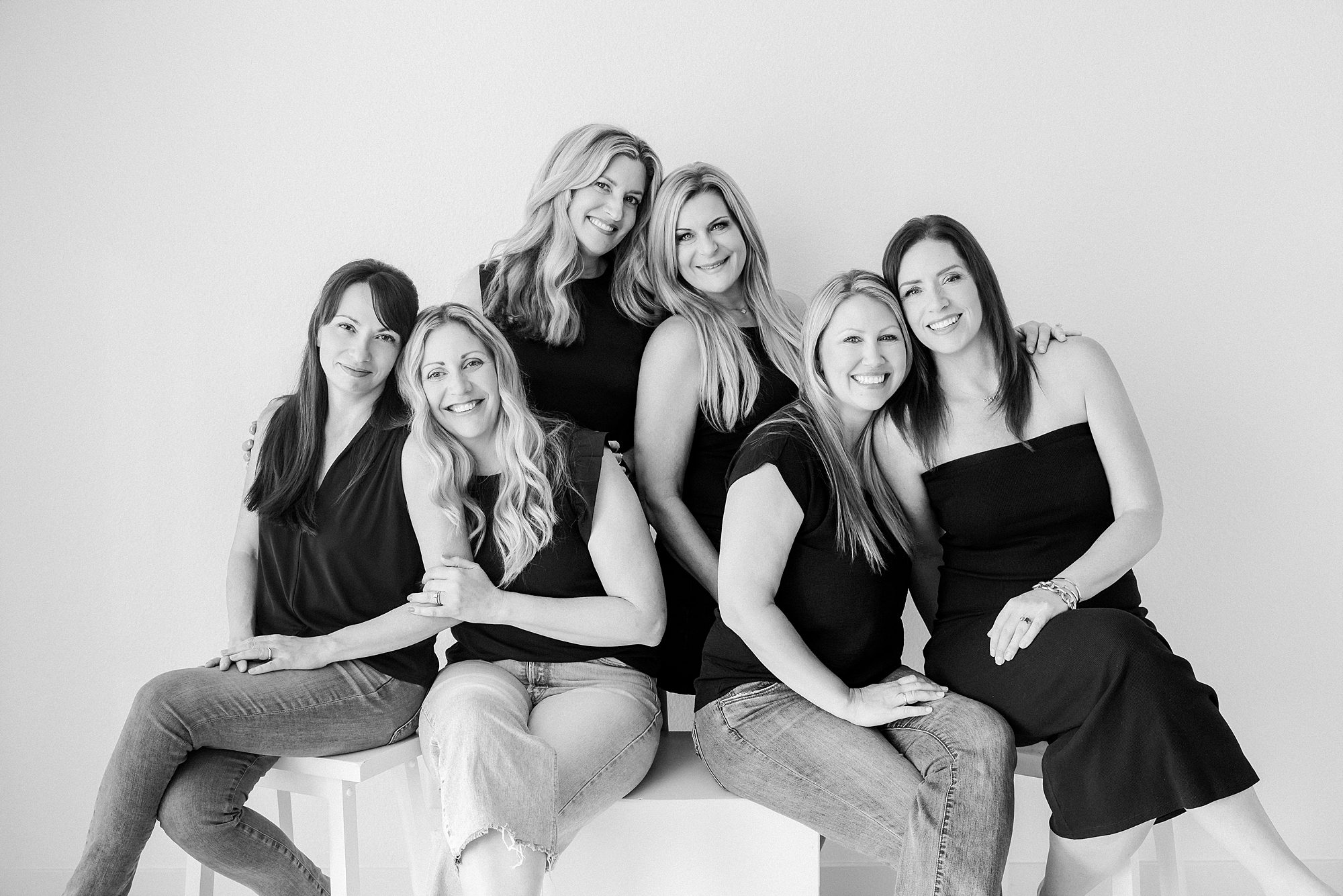 Five women in black shirts posing together for a group portrait.
