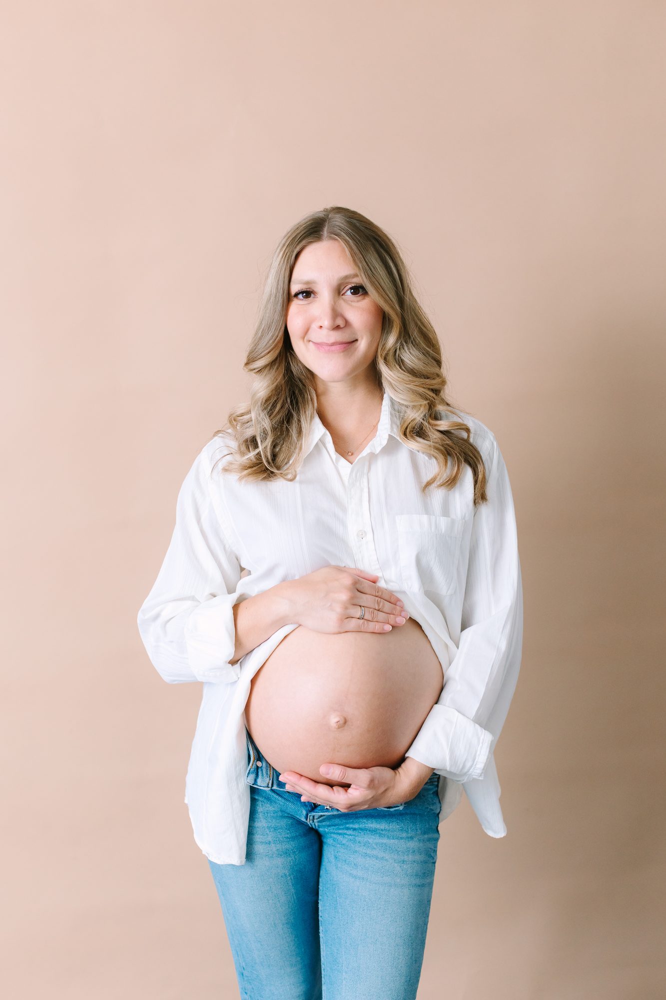 Maternity portrait against a warm tan backdrop in the Carlsbad studio