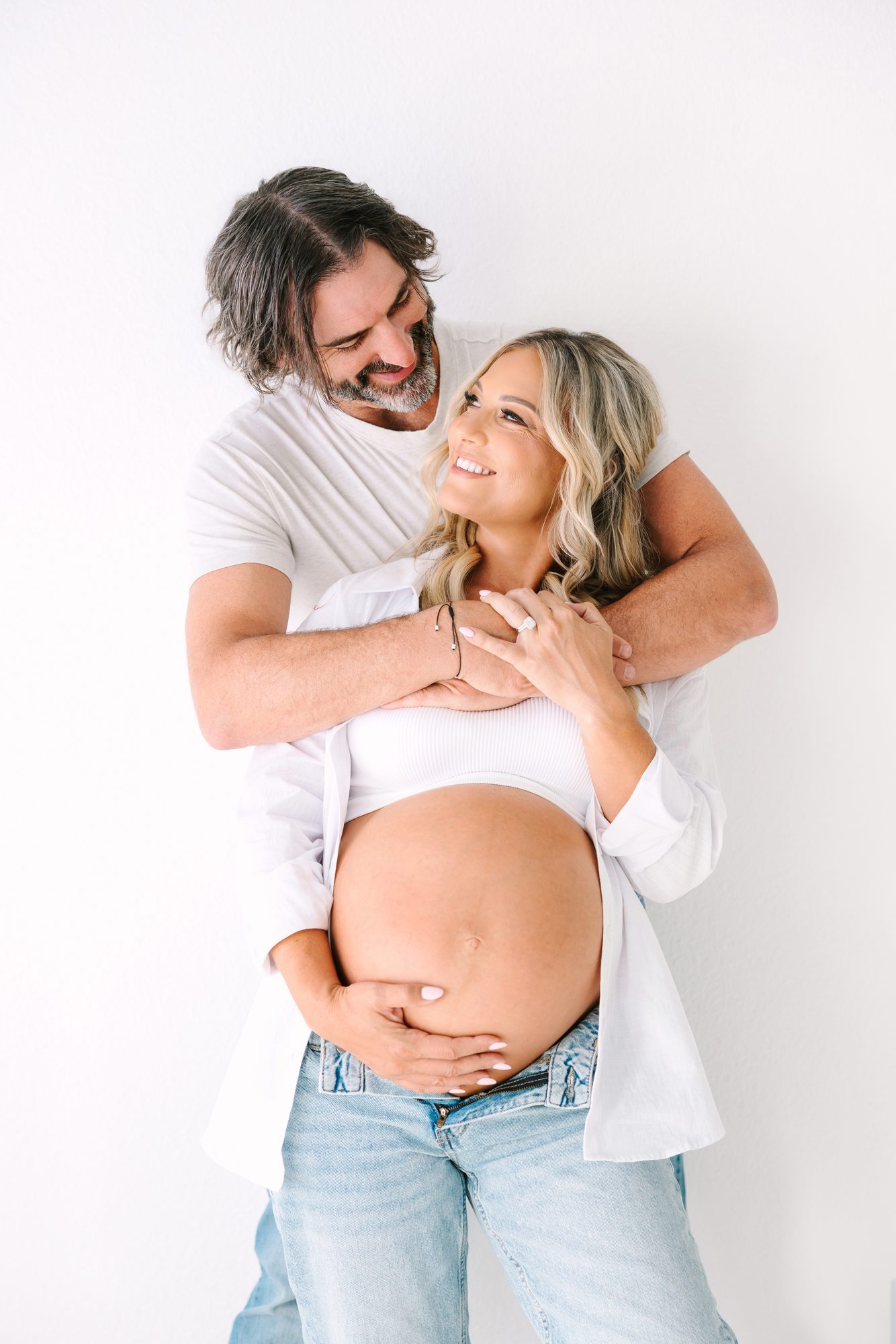 Couple embracing during a studio maternity session in Carlsbad