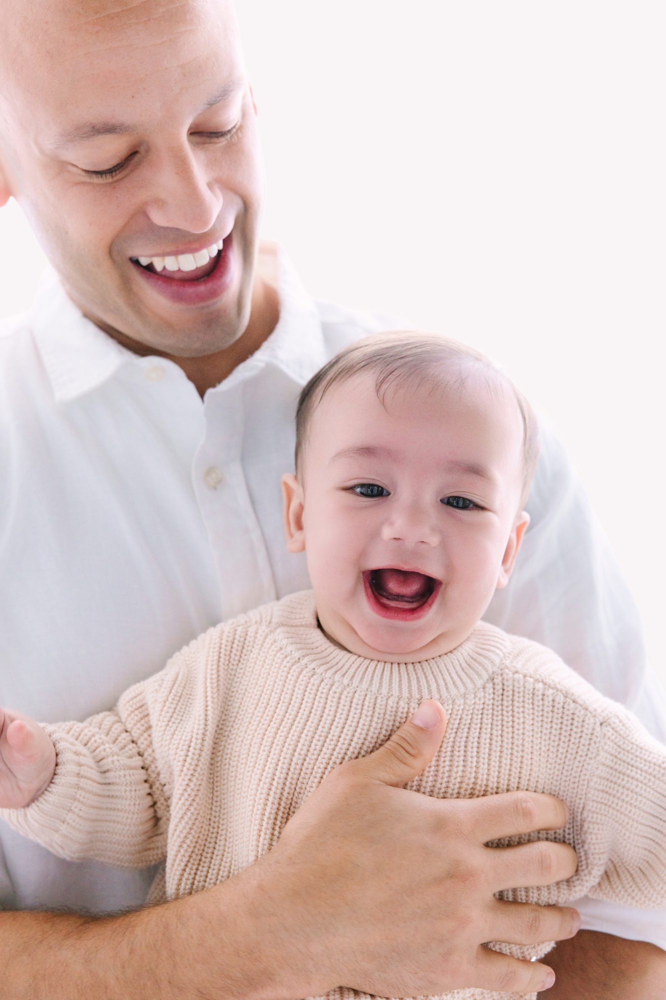 Laughing baby held by dad, studio baby milestone portrait