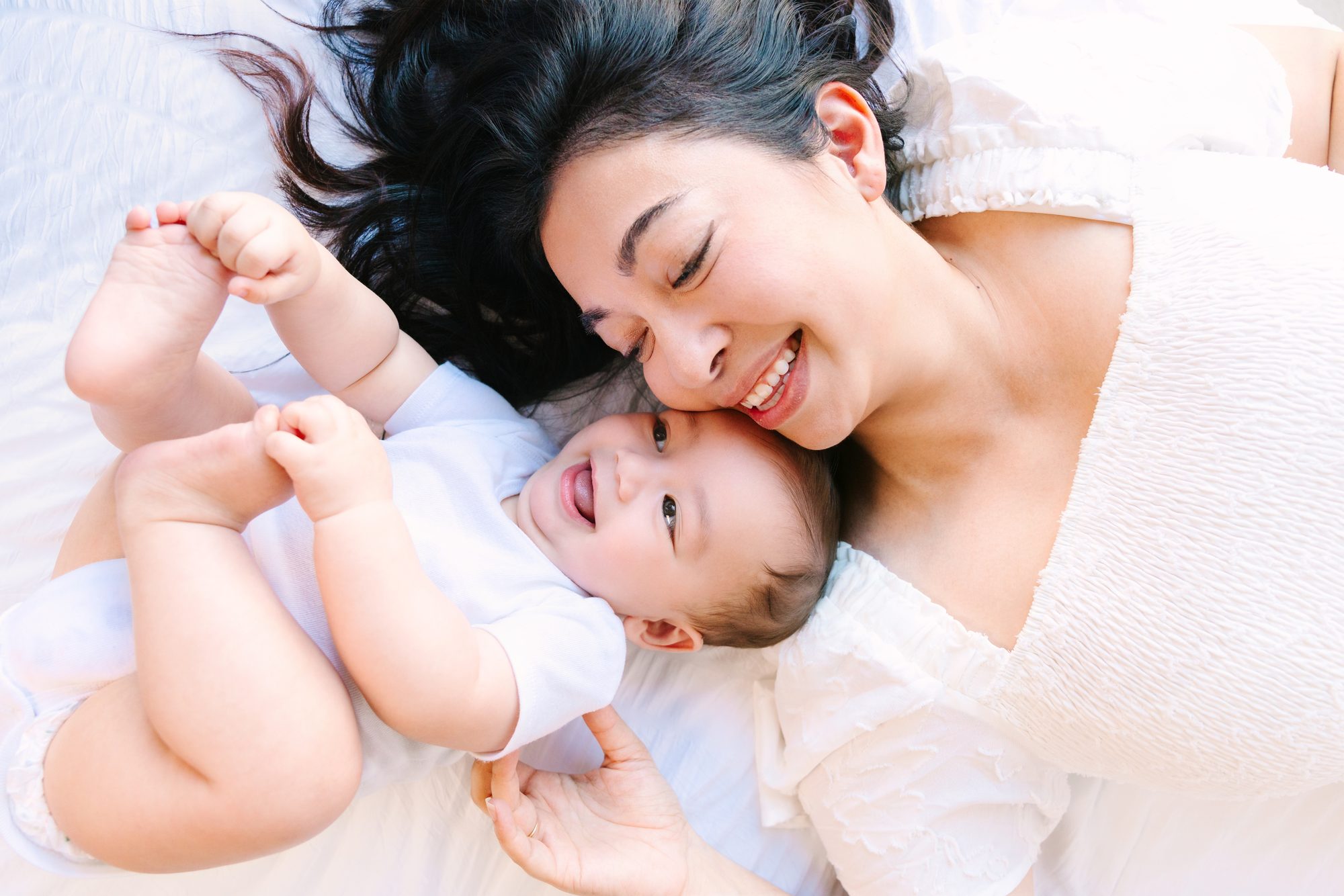Mother and baby lying together and laughing, studio baby portrait