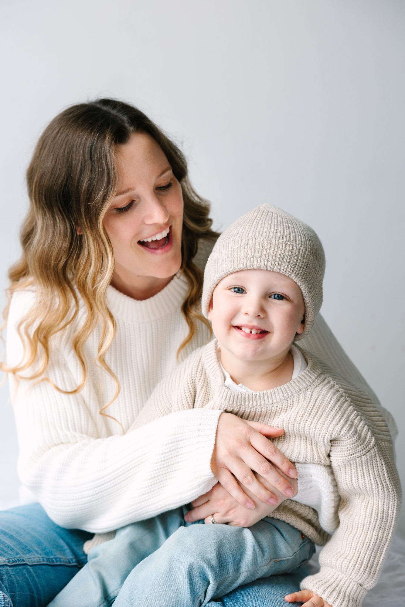 Mother hugging her toddler son, both laughing, in the studio