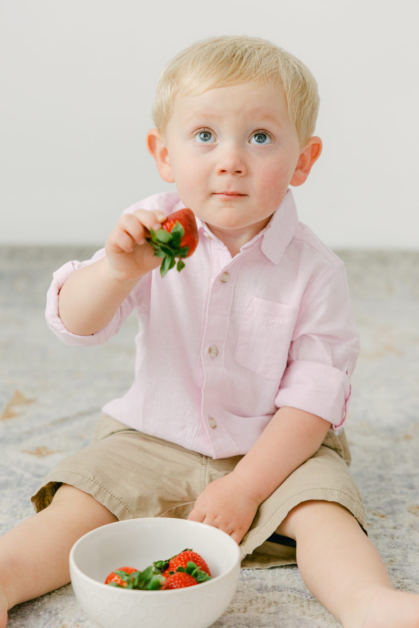 Toddler boy eating a strawberry during a studio portrait session