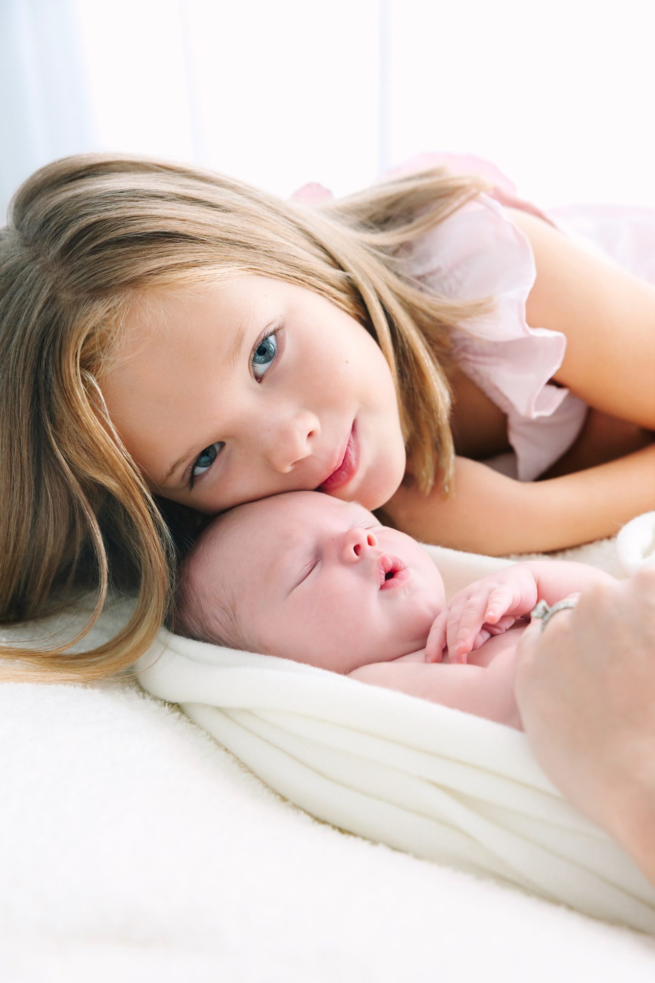 Big sister resting her head on her newborn sibling
